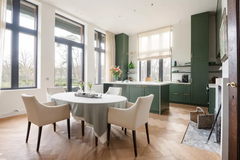 Lichte eetkamer met ronde tafel en groene keuken