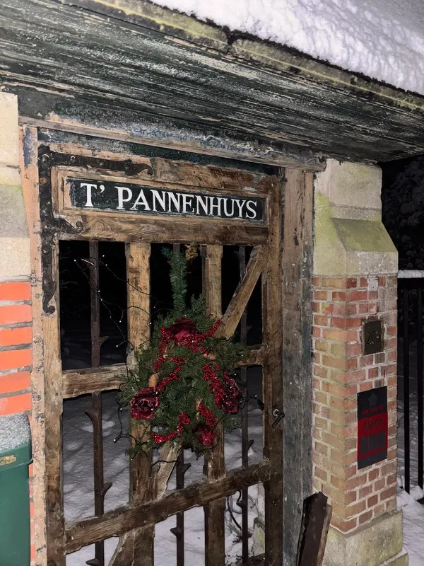 Houten toegangspoort met naambord T' Pannenhuys in de sneeuw
