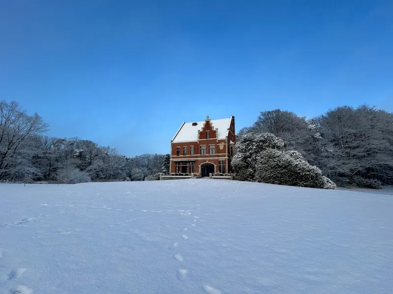 Het kasteel in een besneeuwd park onder een blauwe lucht